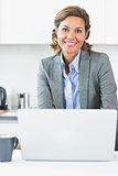 Happy woman using laptop in kitchen