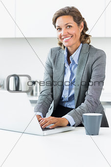 Woman typing on laptop in the kitchen before work