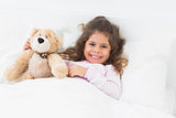 Little girl in bed with teddy bear