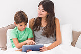 Smiling mother using digital tablet with son