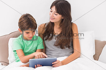 Smiling mother using digital tablet with son