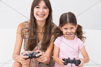 Happy mother and daughter playing video games