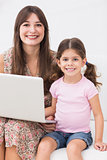 Smiling mother and daughter with laptop