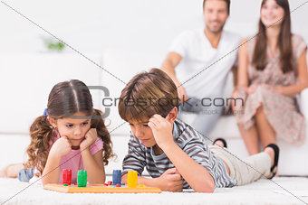 Siblings playing board game on the floor