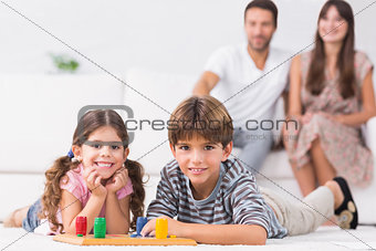 Happy siblings playing board game on floor