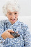 Elderly focused woman using the remote