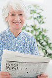 Elderly smiling woman reading newspapers