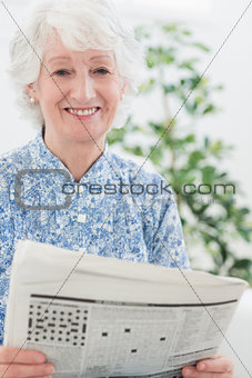 Elderly smiling woman reading newspapers