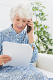Elderly happy woman reading a paper on the phone