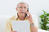 Elderly stern man reading papers on the phone