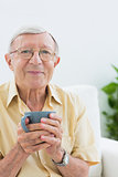 Elderly man looking at camera with a cup