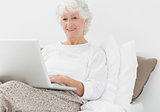 Smiling elderly woman typing on her laptop