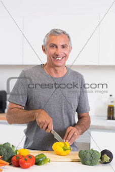 Smiling man cutting a yellow pepper