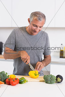 Cheerful man cutting a yellow pepper