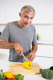 Happy man cutting a yellow pepper