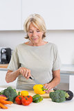 Cheerful woman cutting a yellow pepper