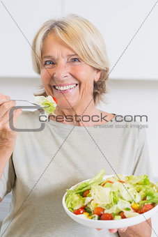 Smiling mature woman eating salad