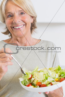 Happy mature woman eating salad