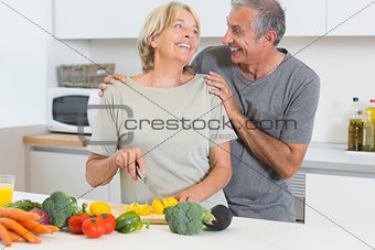Smiling couple cutting vegetables together