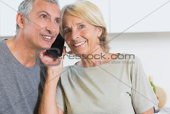 Cheerful mature couple listening a call together