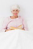 Smiling woman reading in bed
