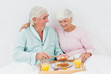 Smiling couple having breakfast in bed