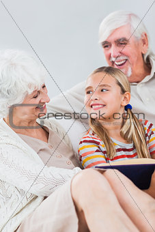 Happy grandparents reading with granddaughter