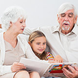 Little girl reading with grandparents