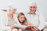 Happy little girl reading with grandparents