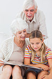 Smiling girl reading with grandparents