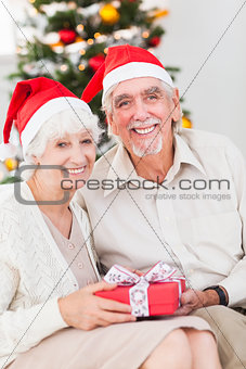 Smiling old couple swapping christmas gifts
