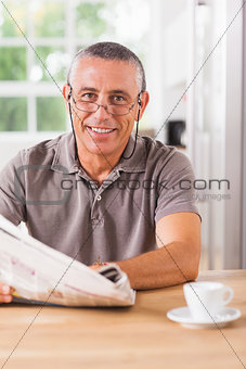 Smiling man reading a newspaper