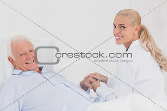 Smiling doctor holding hand of patient
