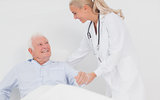 Doctor helping elderly man to sit up