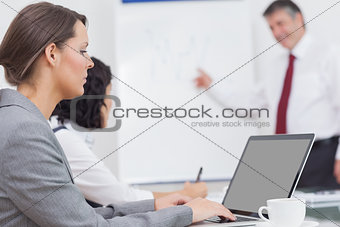 Businesswoman focusing on a laptop during a conference