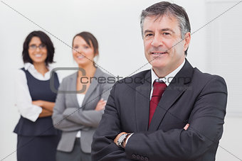 Businessman and his team smiling arms crossed