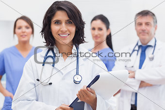 Female doctor with clipboard and her team smiling