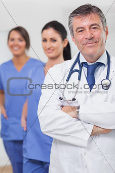 Doctor with arms crossed and his team of nurses