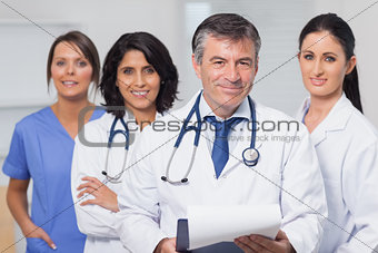 Doctor holding clipboard with his team