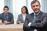 Businessman with arms crossed sitting with business panel