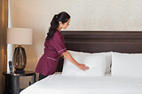 Smiling hotel maid fixing pillows