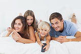 Family lying on the bed with a remote