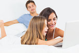 Family sitting with a laptop on the bed