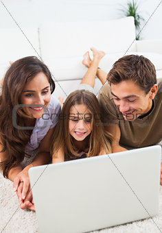 Family lying on a carpet with the laptop