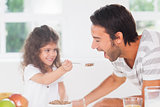 Little girl feeding cereal to father
