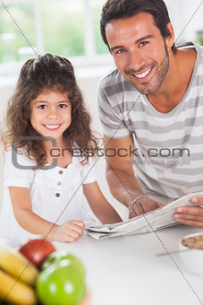 Dad and daughter reading a newspaper during breakfast