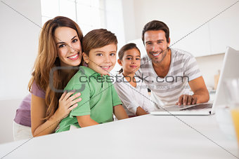 Happy family looking at the camera with a laptop