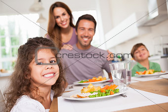Family smiling at the camera at dinner table