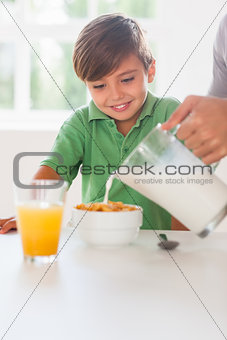 Father pouring milk in the cereal of his son