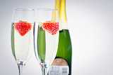 Two champagne flutes with floating strawberries